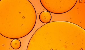 What is Double Cleansing? Oil droplets on orange background.